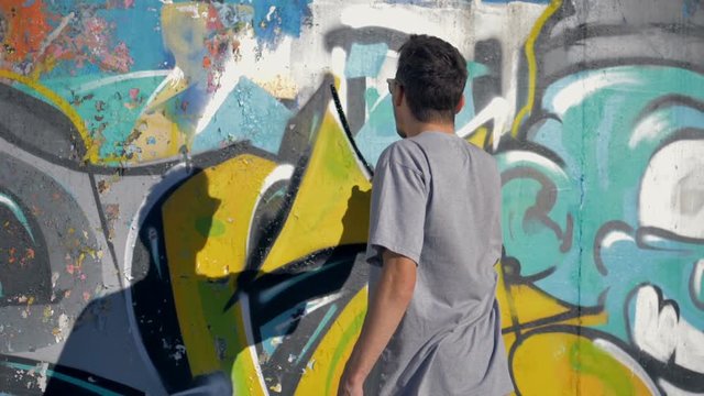 Graffiti artist is painting a black triangle on the yellow letter.
