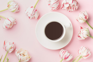 Spring morning concept. Flat-lay of cup of coffee and flowers over light pink background, top view with space for your text