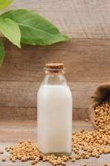 Bottle of soy milk and soybean on wooden table