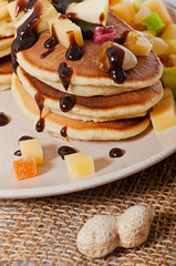 Sweet pancakes with fruits, candied fruits and cheese, homemade, on a light background.