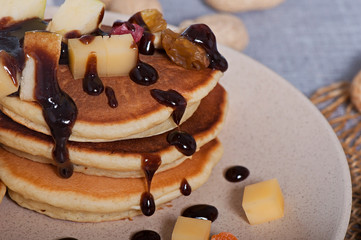 Sweet pancakes with fruits, candied fruits and cheese, homemade, on a light background.