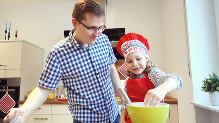 Young father with pretty little daughter backing cookies and having funat home