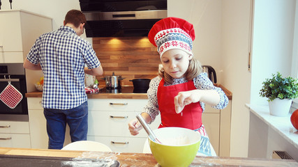 Young father with pretty little daughter backing cookies and having funat home