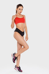 Fototapeta premium Sportive girl in red t-shirt posing standing on gray background