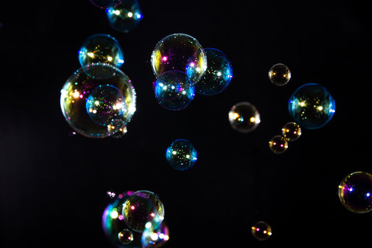 Abstract colorful, rainbow soap bubbles floating in the dark.
