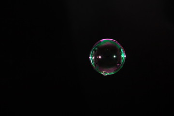 Abstract single of soap bubble floating in the dark.