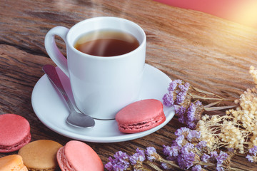 Different types color of macaroons with Cup of hot tea on Old grunge wooden background