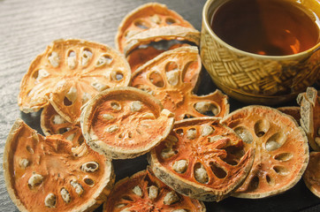 Dried herbs and dried bael fruit, Close-up of bael dry and glass tea and bael juice on the wooden floor, Slices of bael fruit on the dark table.