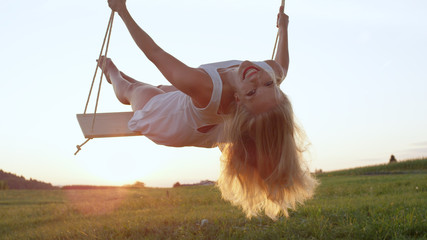 LENS FLARE CLOSE UP: Young blonde woman in white looking back and smiling
