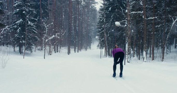 WIDE TRACKING Back view of young adult Caucasian female athlete skiing downhill on a skirun. 4K UHD 60 FPS SLO MO