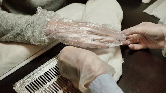 Process paraffin treatment of female hands in beauty salon.