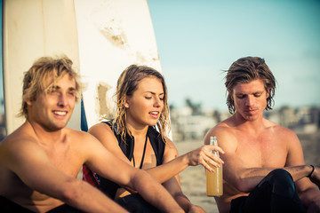 Three surfers relaxing on the beach after sport