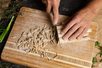 Female's hands cutting noodles roll on chopping board. Close up.