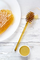 tasty organic honey in a honeycomb and honey lip balm on a wooden, vintage background
