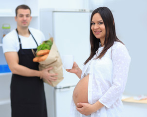 Happy pregnant couple of vegetarians in the kitchen.