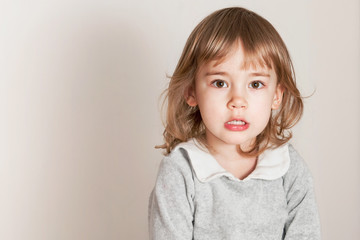 Unhappy little baby girl on light background
