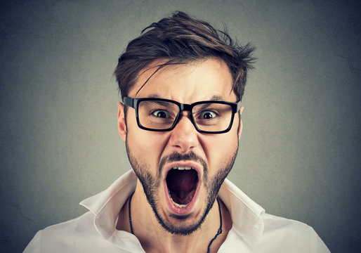 Young angry man looking at camera and screaming