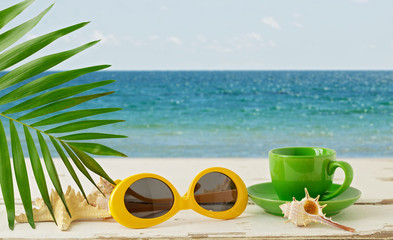 Fototapeta na wymiar Summer seascape. Relax on the beach, a cup of coffee and sunglasses.