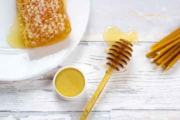 organic honeycomb, honey lip balm and natural wax candles on wooden white bakcground