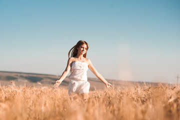Fototapeta na wymiar Happy girl running in rye field outdoors. Freedom. Happiness.
