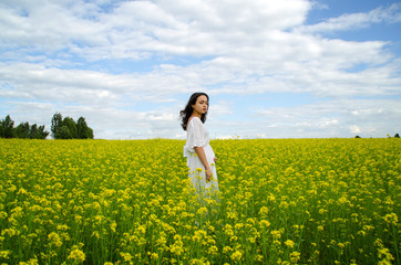 Fototapeta premium beautiful young girl in a white dress in a field of flowers
