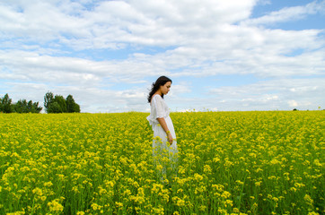 Fototapeta premium beautiful young girl in a white dress in a field of flowers