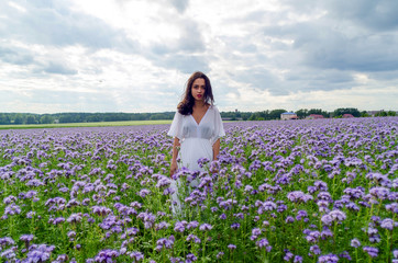 beautiful young girl in a white dress in a field of flowers