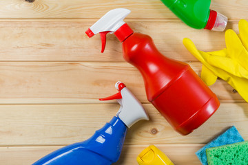 Cleaning concept - cleaning supplies on wood background