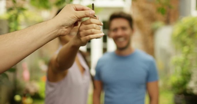 4K Happy couple in front of new home, taking the key from real estate agent. Slow motion.
