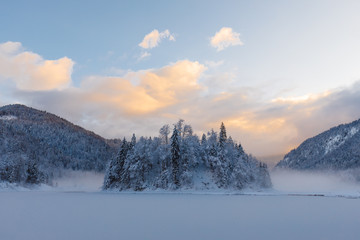 sunset at lake Weitsee in winter with smoke on water