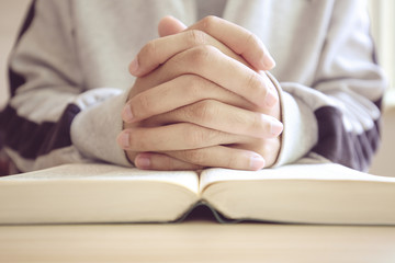 Praying on a wooden table with an open Bible