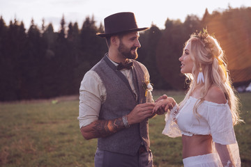 Fototapeta premium Lovely young couple in wedding dresses in Bohho style, on a field with a balloon
