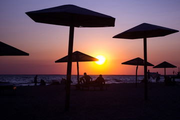 Father and children playing on the beach at the sunset time. Concept of friendly family.