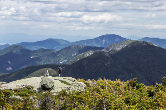 Hiker walking on beautiful mountain path with sweeping views into the Adirondack high peaks in New York