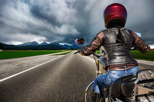 Biker girl on a motorcycle hurtling down the road in a lightning storm - Forggensee and Schwangau, Germany Bavaria