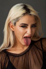 Blonde woman portrait wearing black tulle shirt with tongue stuck out