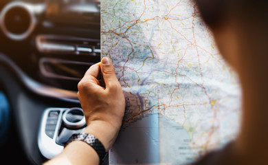 Hipster man holding in male hands and looking on navigation map in auto, tourist traveler hiker...