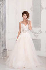 Obraz premium Morning of the bride. A beautiful bride stands in a wedding dress. Hand at the face. Dress with lace.