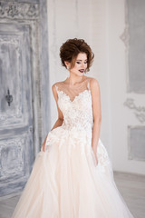 Morning of the bride. A beautiful bride stands in a wedding dress. Wedding hairstyle and makeup. Dress with lace.