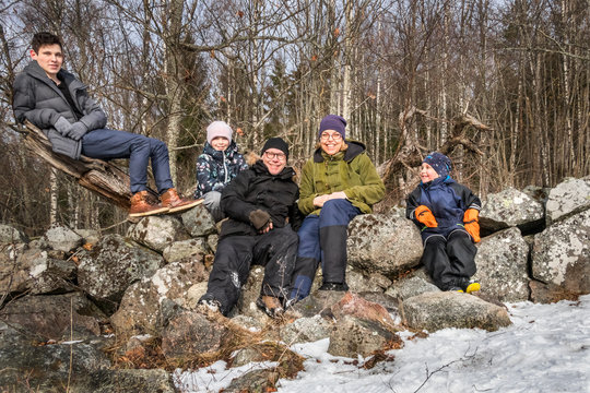 Winter family portrait outdoors. Parents and children leaning against a stone wall.