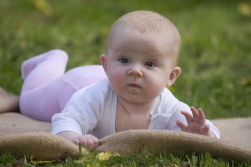 Süßes Baby liegt auf dem Bauch auf dem Rasen im Garten