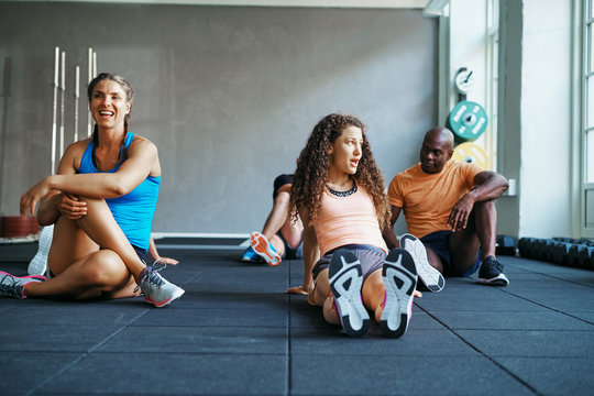 People relaxing together on a gym floor after working out