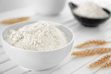 Bowl with wheat flour on white table, closeup