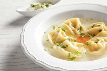 Tasty broth with dumplings on wooden table