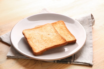 Plate with tasty toasted bread on wooden table