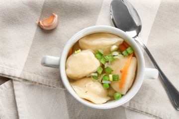 Tasty broth with dumplings on table