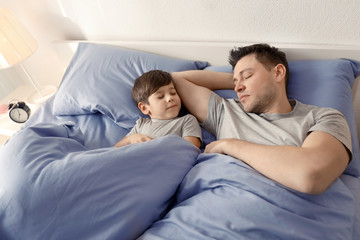 Father with son sleeping in bed at home