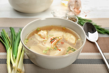 Bowl with tasty broth and dumplings on table
