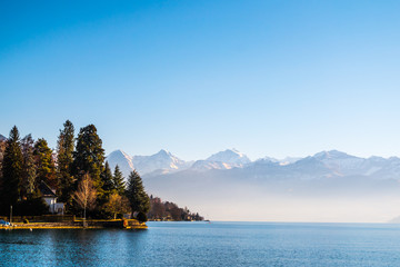 Lake Thun and typical Switzerland village near town of Interlaken with a view of Alps mountain at background