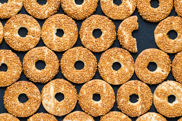 Round cookies with sesame seeds on a black background, one cookie is not such as all.